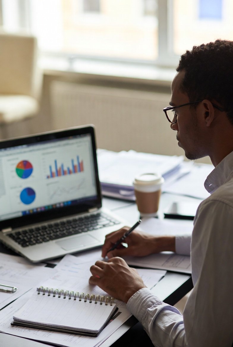 A freelance data analyst reviewing dashboards, spreadsheets, and charts on multiple screens during a client project